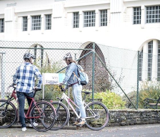 Cyclists at the art nouveau power station in Heimbach, © Dennis Stratmann | Grünmetropole e.V. Cyclists at the art nouveau power station in Heimbach, © Dennis Stratmann | Grünmetropole e.V.