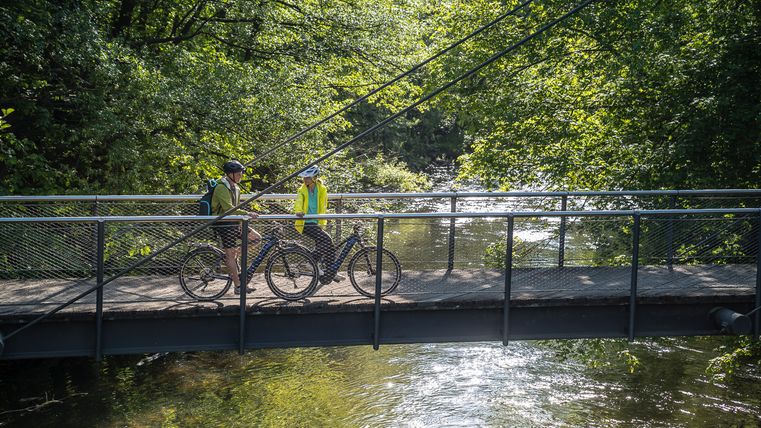 Radfahrende auf der Rurbrücke am Nationalpark-Infopunkt Zerkall