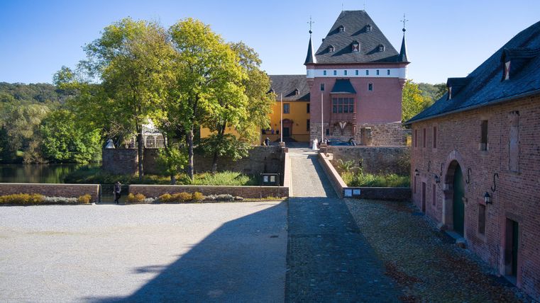 Eine hübsche Burg mit einem klaren blauen Himmel. Umgeben von grünen Bäumen und einer ruhigen Umgebung.