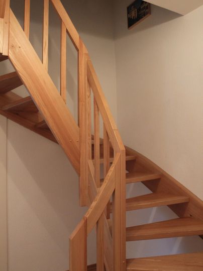 Eine elegante Holztreppe führt nach oben. Die Wände sind schlicht und in hellen Farben gehalten.