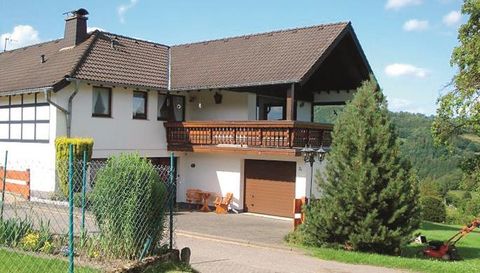 Ein gemütliches Haus mit einem Balkon und einer Garage. Umgeben von grüner Landschaft und einem schönen Garten.