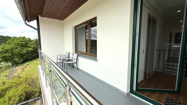Ein moderner Balkon mit Blick auf die Natur. Zwei Stühle stehen bereit zum Entspannen.