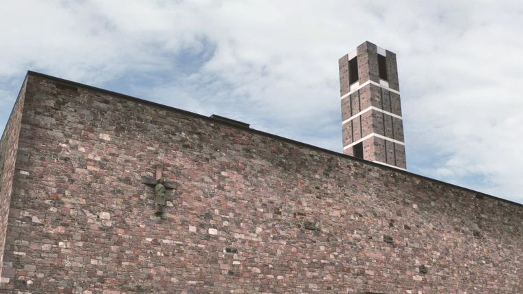 Ein modernes Gebäude aus Stein mit einem hohen Schornstein. Der Himmel ist bewölkt.