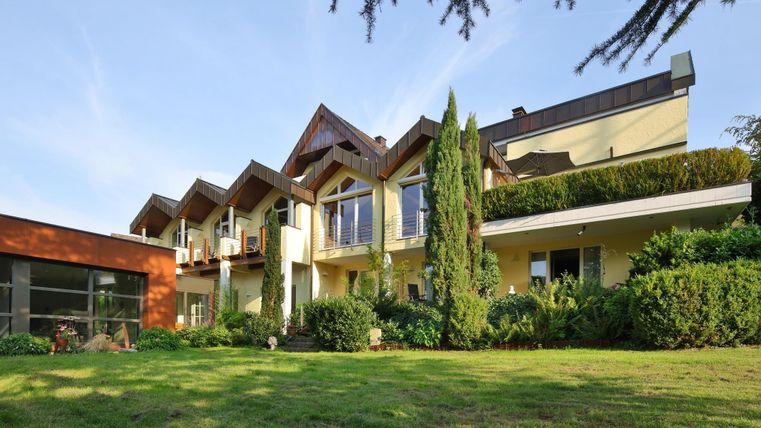 Ein modernes Haus mit einem gepflegten Garten und großen Fenstern. Die Architektur ist ansprechend und kombiniert Holz- und Glaselemente.