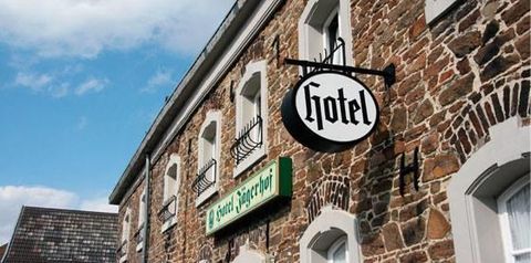 Ein Hotel mit einem traditionellen Schild hängt an der Fassade. Der Himmel ist klar und es ist tagsüber.