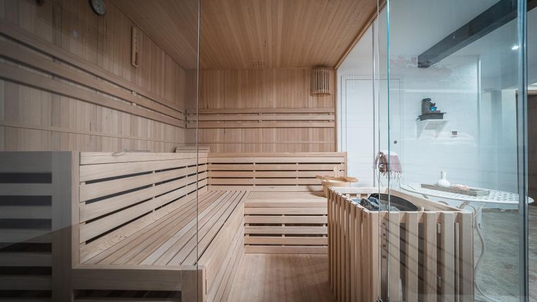 Eine moderne Sauna mit Holzvertäfelung und Sitzbänken. Der Raum ist hell und einladend gestaltet.