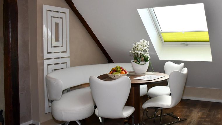 Ein stilvoller Essbereich mit einem runden Tisch und modernen Stühlen. Große Fenster ermöglichen viel Tageslicht und schaffen eine helle Atmosphäre.