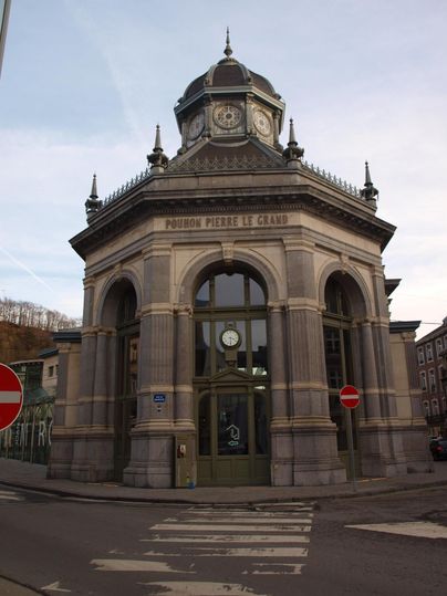 Ein historisches Gebäude mit einer markanten Architektur und einem Kuppeldach. Die Fassade ist reich verziert und steht an einer Straßenecke.
