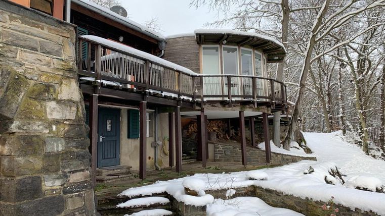 Ein modernes Holzhaus in einer schneebedeckten Umgebung. Die große Terrasse bietet eine schöne Aussicht auf die winterliche Landschaft.
