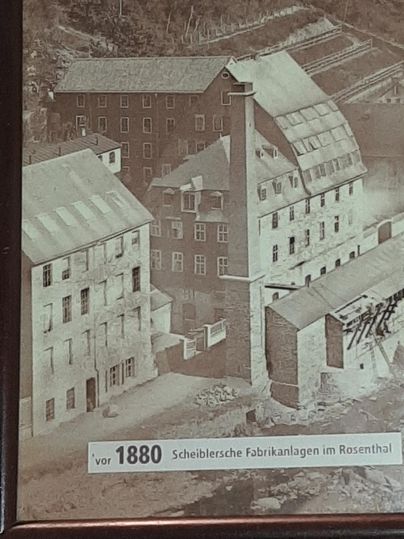 Eine historische Fotografie von Fabrikgebäuden im Rosenthal vor 1880. Die Anlage zeigt mehrere Gebäude und einen hohen Schornstein.