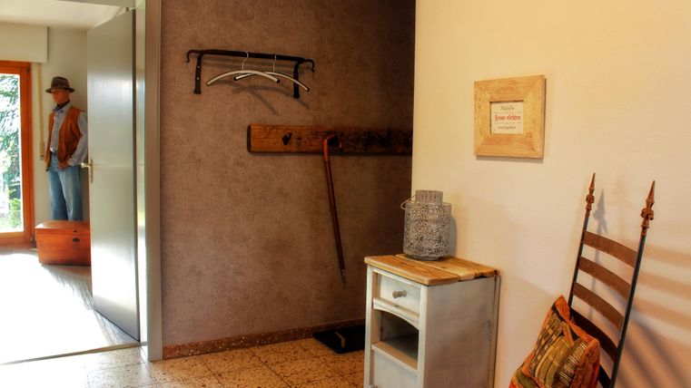 Ein einladender Flur mit einer offenen Tür und einem Möbelstück. An der Wand hängen eine Garderobe und eine dekorative Tafel.