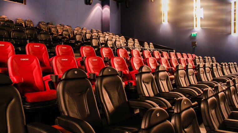 Ein modernes Kino mit einer Reihe von roten und schwarzen Sitzen. Die Sitze sind bequem und stehen bereit für die Zuschauer.