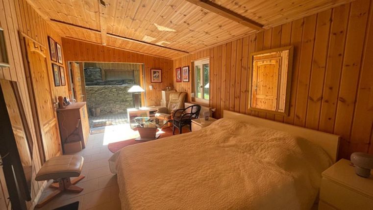 Ein gemütliches Schlafzimmer mit Holzvertäfelung und einem großen Bett. Natürliches Licht fällt durch die Fenster und schafft eine einladende Atmosphäre.