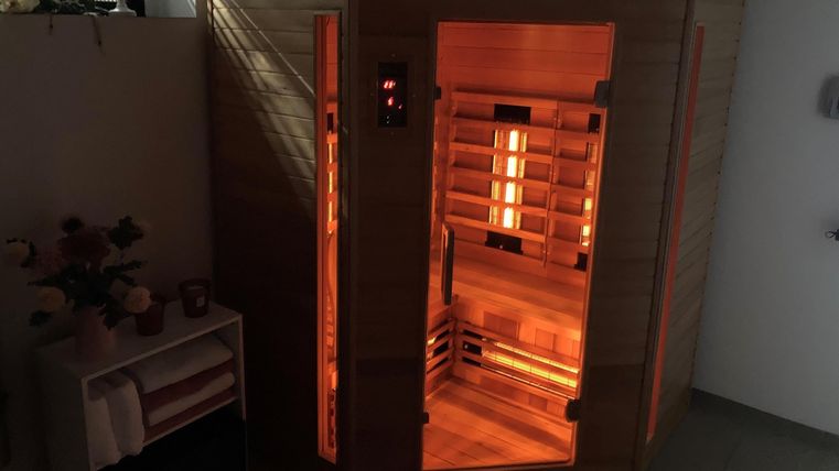 Eine moderne Sauna aus Holz mit warmem, orangefarbenem Licht. Die Inneneinrichtung ist gemütlich und einladend.