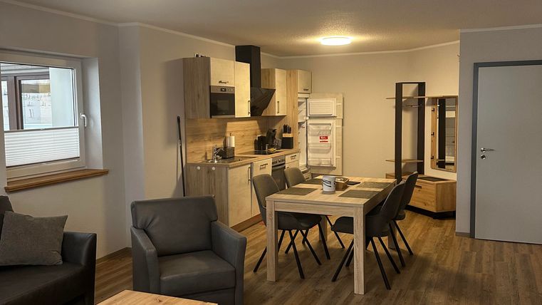 Eine moderne Wohnung mit einer offenen Küche und einem Essbereich. Der Raum ist hell und freundlich, mit Holzfußboden und gemütlichen Möbeln.