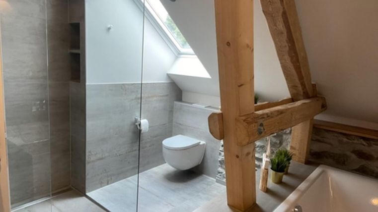 Ein modernes Badezimmer mit einer Glasdusche und einer freistehenden Badewanne. Die Holzstruktur verleiht dem Raum eine warme, einladende Atmosphäre.