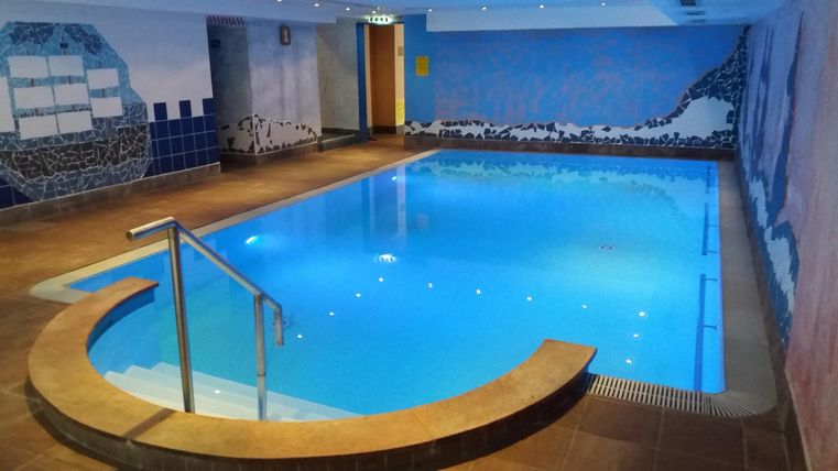 Ein eleganter Innenpool mit klarem Wasser und flauschigen Liegen. Die Wände sind farbenfroh mit schönen Malereien dekoriert.