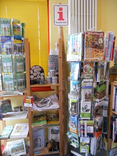 Ein kleines Touristeninformationszentrum mit Prospekten und Karten. Auf einem Regal sind verschiedene Informationsmaterialien über die Region zu sehen.