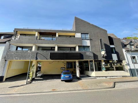 Ein modernes Gebäude mit mehreren Etagen und einem flachen Dach. Vor dem Gebäude steht ein blauer Pkw auf der Straße.