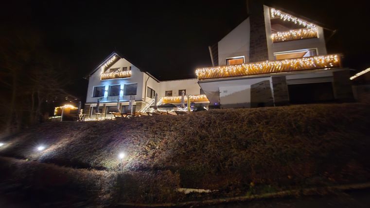 Ein modernes Haus mit festlicher Beleuchtung in der Nacht. Die Lichter erhellen die Fassade und umgebenen Bereiche.