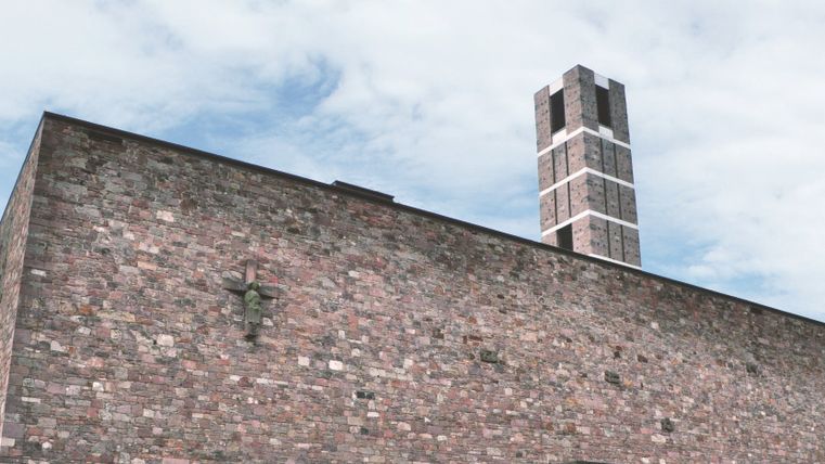Ein modernes Gebäude mit einer interessanten Steinfassade und einem hohen Schornstein. Der Himmel ist leicht bewölkt.