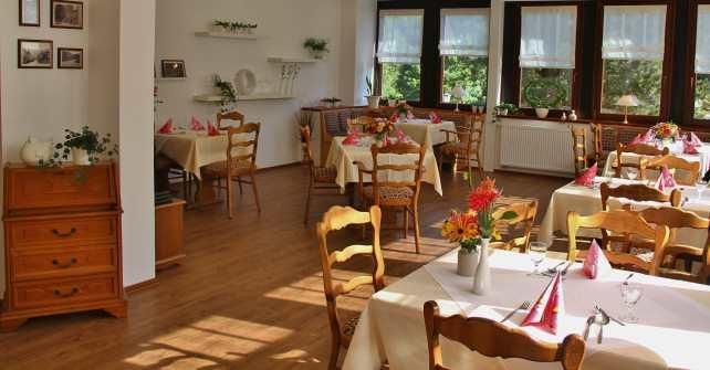 Ein gemütliches Restaurant mit hellen Fenstern und geschmackvoll gedeckten Tischen. Die warmen Holztöne schaffen eine einladende Atmosphäre.