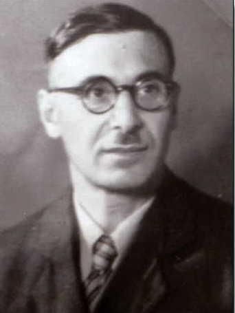 Ein Schwarz-Weiß-Porträt eines Mannes mit Brille und Anzug. Er schaut in die Kamera und hat eine neutrale Miene.