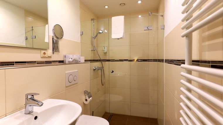 Ein modernes Badezimmer mit einer Dusche und einem Waschbecken. Helle Fliesen und eine angenehme Atmosphäre zeichnen den Raum aus.