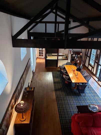 Eine elegante Wohnung mit Holzboden und hohen Decken. Der Raum ist modern eingerichtet mit einem großen Tisch und einer gemütlichen Couch.