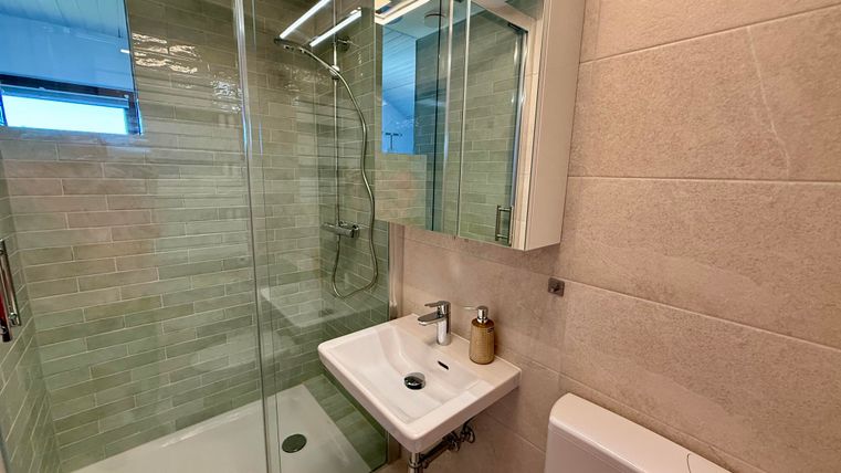 Ein modernes Badezimmer mit einer Glasdusche und einem Waschbecken. Die Wände sind in neutralen Farbtönen gehalten.