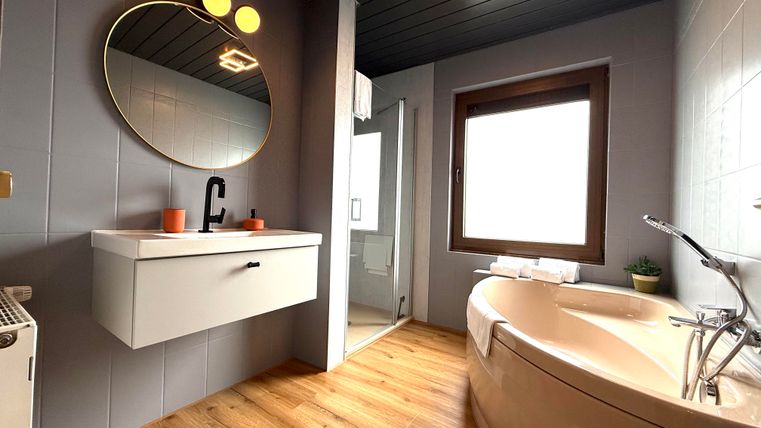 Ein modernes Badezimmer mit einem runden Spiegel und einem freistehenden Badewanne. Die Wände sind in sanften Farben gestrichen und der Boden besteht aus Holz.