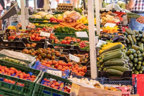 Ein bunter Markt mit frischem Obst und Gemüse in verschiedenen Kisten. Die Vielfalt an Farben und Formen macht die Atmosphäre lebhaft und einladend.
