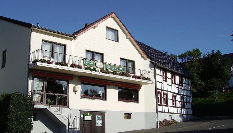 Ein charmantes Gebäude mit einem begrünten Eingangsbereich. Die Fassade ist freundlich und einladend, mit Blumen auf dem Balkon.
