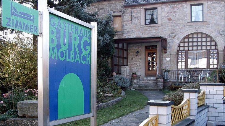 Ein charmantes Gästehaus mit dem Namen „Burg Molbach“. Es ist von einem schön angelegten Garten umgeben.