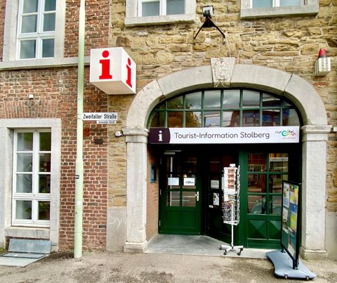 Ein Eingangsbereich der Stolberg-Touristik mit einem großen Schild. Neben dem Eingang steht ein zusätzliches Schild mit Informationen für Besucher.