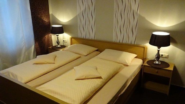 Ein gemütliches Schlafzimmer mit einem Doppelbett und zwei Nachttischen. Die Wände sind in sanften Farben gehalten, und sanftes Licht spielt eine einladende Atmosphäre.