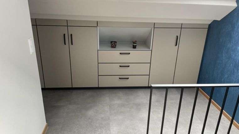 Ein moderner Raum mit einem hellen Farbton und einem praktischen Schrank-Design. Die Wände sind teils weiß und teils in einem angenehmen Blauton gestrichen.