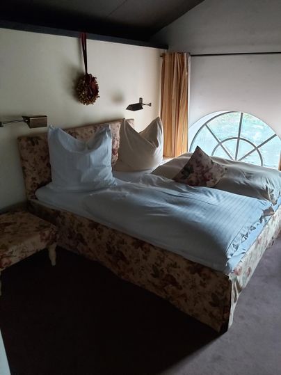 Ein gemütliches Schlafzimmer mit einem großen Bett und einem schönen Fenster. Die Wände sind in neutralen Farben mit dekorativen Vorhängen.