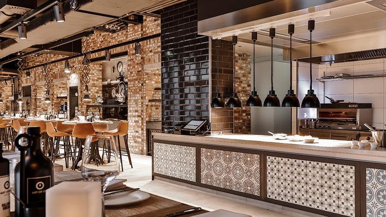 Ein modernes Restaurant mit einer offenen Küche und stylischem Interieur. Die Atmosphäre ist einladend, mit eleganten Barstühlen und einer gut gestalteten Essensauswahl.