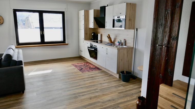 Eine moderne Wohnung mit offener Küche und einem gemütlichen Sofa. Der Raum hat helle Wände und einen schönen Holzboden.