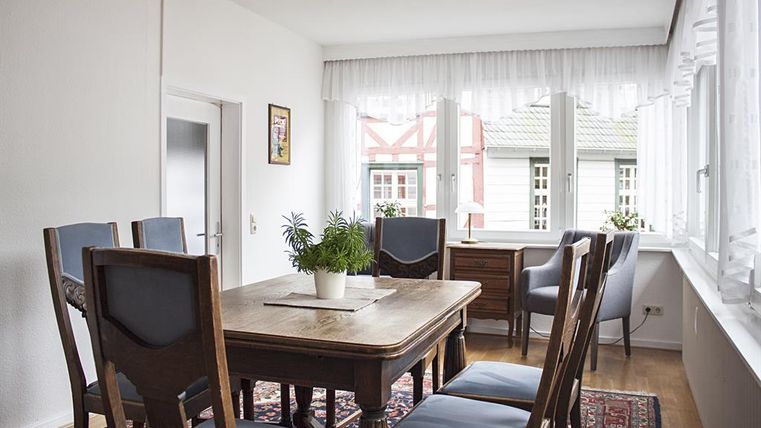 Ein helles Esszimmer mit einem Holztisch und Stühlen. Große Fenster sorgen für viel Tageslicht und eine angenehme Atmosphäre.