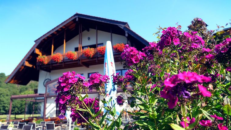 Ein schönes Gebäude mit Blumenkästen und bunten Blumen im Vordergrund. Der Himmel ist klar und blau.