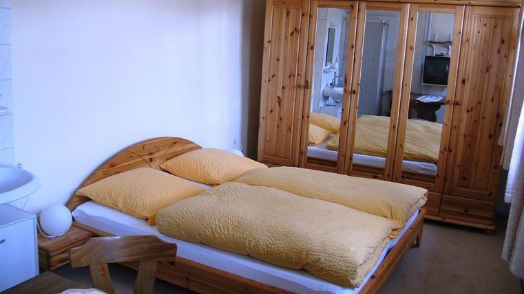 Ein gemütliches Schlafzimmer mit einem Doppelbett und Möbeln aus Holz. Der Raum hat eine helle Atmosphäre und einen großen Kleiderschrank mit Spiegeln.