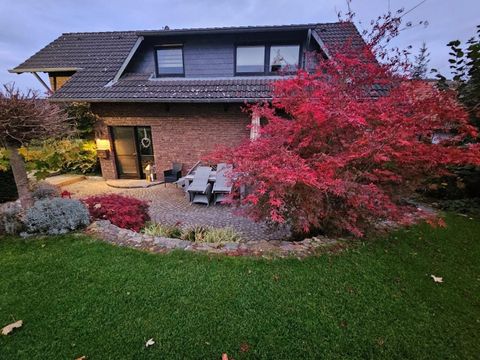 Ein charmantes Haus mit einem gepflegten Garten. Ein schöner roter Baum sorgt für herbstliche Farben.