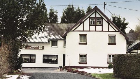 Ein charmantes Haus im Landhausstil mit einem hellen Äußeren. Umgeben von Bäumen und einem kleinen Garten.