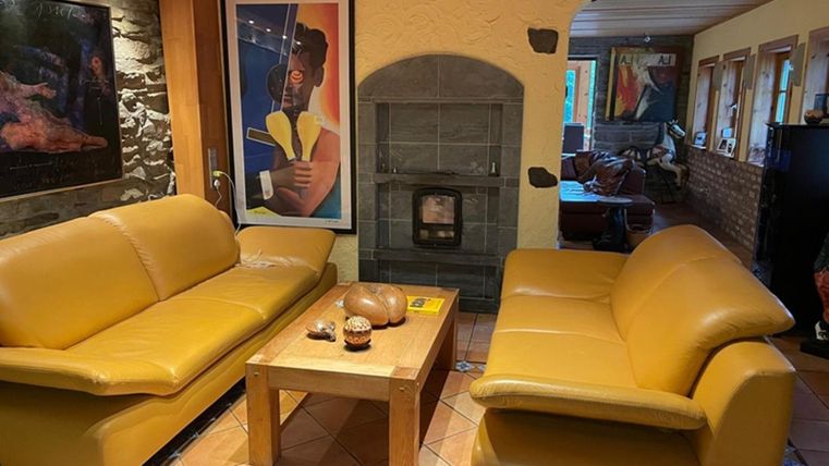 Ein gemütliches Wohnzimmer mit zwei gelben Sofas und einem Holztisch. Im Hintergrund ist ein Kamin und dekorative Kunst an den Wänden zu sehen.