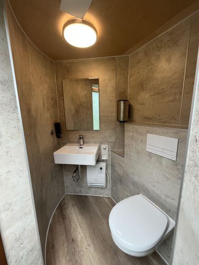 Ein modernes Badezimmer mit einer Toilette und einem Waschbecken. Die Wände sind in neutralen Farben gehalten und der Raum ist gut beleuchtet.