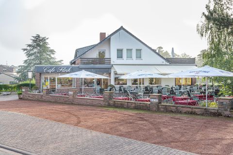 Ein gemütliches Café mit einem Außenbereich und Sonnenschirmen. Die Umgebung ist ruhig und einladend.