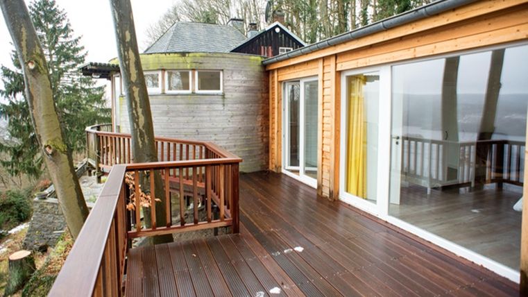 Eine moderne Holzterrasse umgeben von Bäumen. Der Blick auf die Landschaft ist klar und einladend.