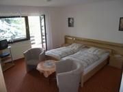 Ein gemütliches Hotelzimmer mit zwei Einzelbetten. Es gibt einen kleinen Tisch und zwei Sessel sowie einen Balkon mit Aussicht.